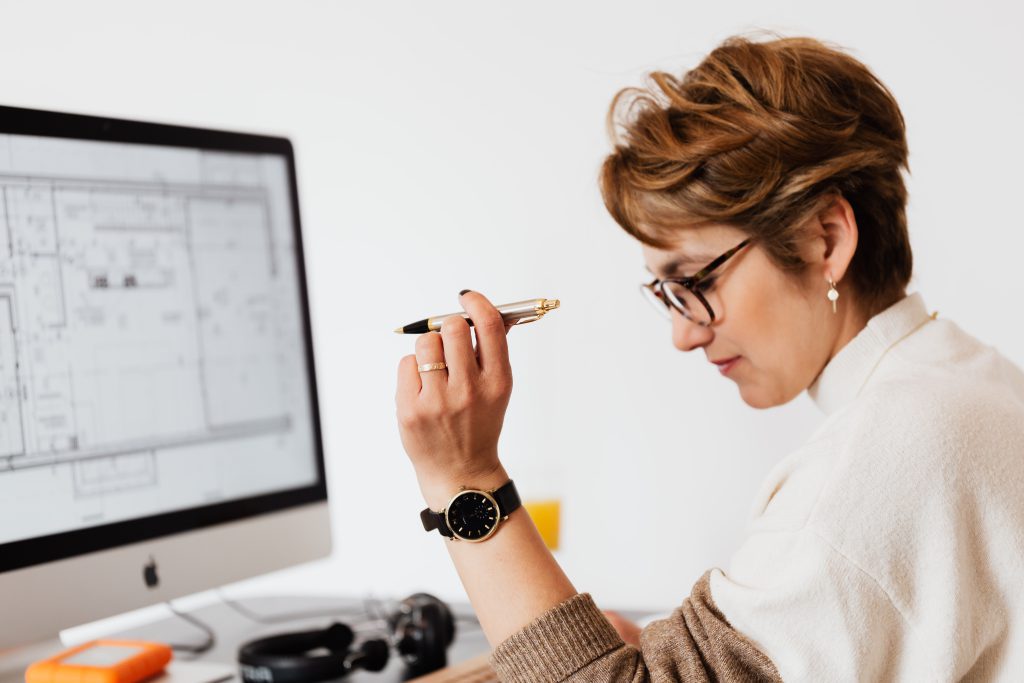 Femme sur son bureau entrain d'étudier un plan architecte ou un plan en béton armé